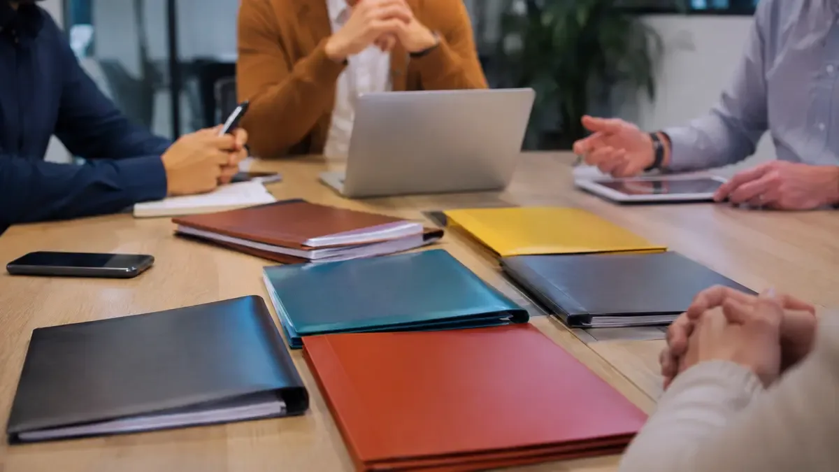 Carpetas de distintos colores ordenadas como una cartera diversificada en una sala de reunión de una pyme, plano medio